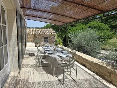 a patio with a table and chairs on a deck at Mas Cerisiers in Saint-Martin-de-Castillon