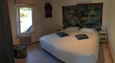 a bedroom with a large white bed with a window at Gîtes L'HERMITAGE in La Tour-dʼAigues