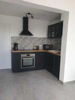 a kitchen with black cabinets and a stove at Gîtes L'HERMITAGE in La Tour-dʼAigues