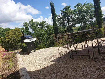 a grill and a bench sitting on top of gravel at Gîtes L'HERMITAGE in La Tour-dʼAigues
