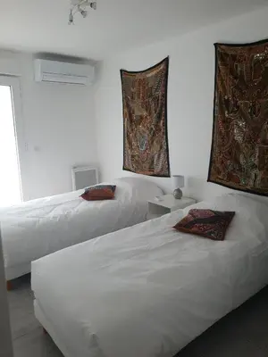 two beds in a room with white walls at Gîtes L'HERMITAGE in La Tour-dʼAigues