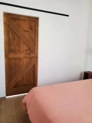 a bedroom with a wooden door and a bed at Rêve en Lubéron in Lauris