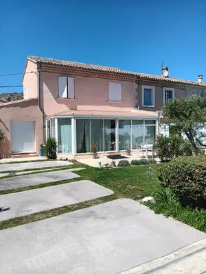 a large pink house with glass doors and a yard at La villa MARIE in Cavaillon