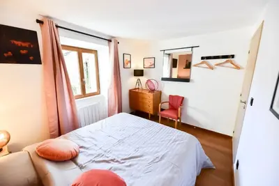a small bedroom with a bed and a chair at Charmante maison de village au coeur du Luberon in Cucuron