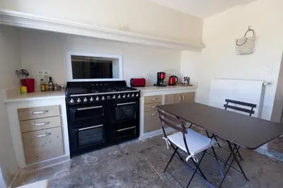 a kitchen with a black stove and a table at Château La Croix Des Pins in Mazan