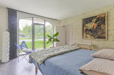 a bedroom with a bed and a chair and a window at Mas Le Cerf in Eyragues