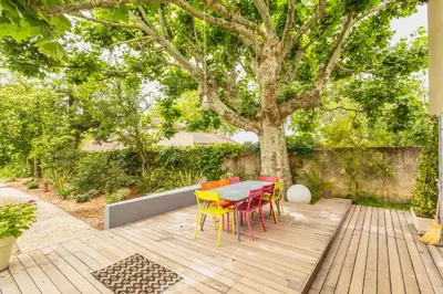a table and chairs on a wooden deck with a tree at Mas Le Cerf in Eyragues