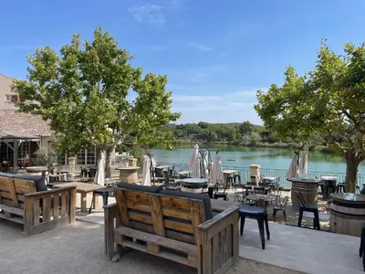 a restaurant with tables and chairs next to a river at LES CISTES in Mallemort