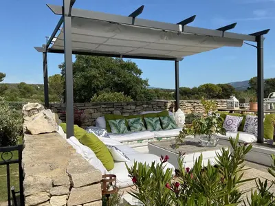 a pergola with a couch and pillows on a patio at Chambre d'hôtes chez Maguy B-Villa Makeire in Gordes