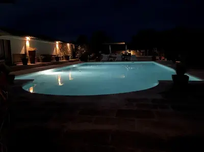 a large swimming pool lit up at night at Chambre d'hôtes chez Maguy B-Villa Makeire in Gordes