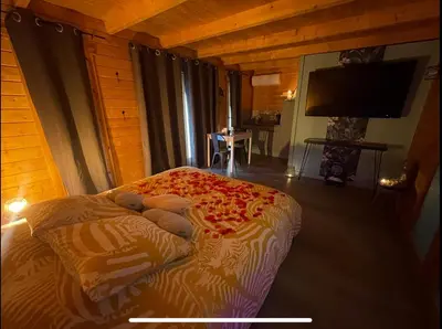 a bedroom with a bed in a room with a tv at Une Pause Douceur - Suite All in Wood in Eyguières