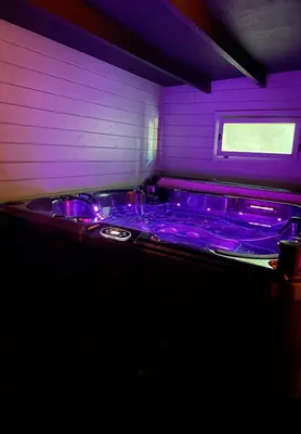 a purple room with a jacuzzi tub with purple lighting at Une Pause Douceur - Suite All in Wood in Eyguières