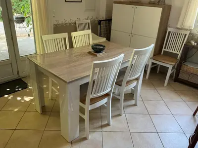 a dining room table with white chairs and a kitchen at Les Tournesols in Saint-Andiol