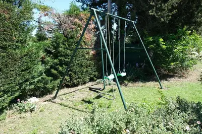 an empty swing set in a garden at mas attached to another building with private pool 4 people in carpentras, at the foot of the ventoux in provence. in Carpentras