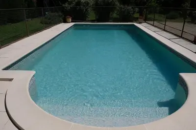 a large swimming pool with blue water at mas attached to another building with private pool 4 people in carpentras, at the foot of the ventoux in provence. in Carpentras