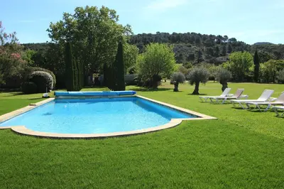a swimming pool in the middle of a lawn with chairs at magnificient property with heated swimming-pool in the luberon - 14 persons in Les Taillades