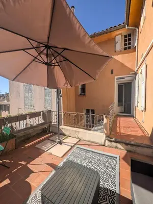 a patio with an umbrella and a bench on a balcony at UNE TERRASSE SUR LES TOITS in Aix-en-Provence