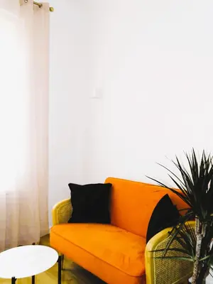 an orange couch in a living room with a table at AUGUSTINS FOUNTAIN Studio Cosy AIX Centre Historique à 3 minutes de COURS MIRABEAU -WIFI-SMART TV-RUE CALME in Aix-en-Provence