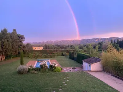 a rainbow in the sky over a yard with a pool at En Provence, Chez Stéphanie et Marcel in Saint-Rémy-de-Provence