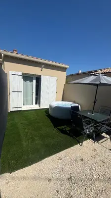 a patio with an umbrella and a table and a chair at Cosy House in Carpentras