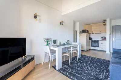 a living room with a table and chairs and a kitchen at Charmant T3 proche centre ville avec parking in Aix-en-Provence