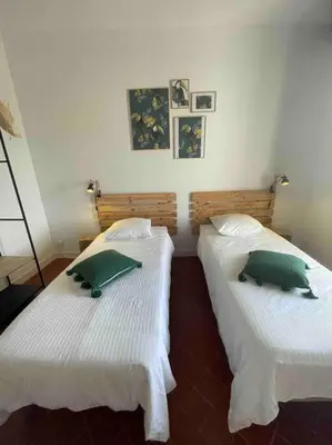 two beds in a room with green pillows on them at Maison de village in Pernes-les-Fontaines