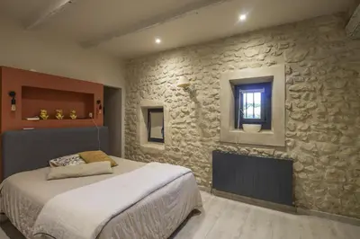 a bedroom with a bed and a stone wall at Le Mas des Oliviers in Châteaurenard