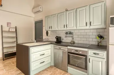a kitchen with white cabinets and stainless steel appliances at Gite neuf avec piscine Bio uv in Saint-Saturnin-les-Apt