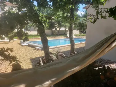a hammock in front of a swimming pool at Gite neuf avec piscine Bio uv in Saint-Saturnin-les-Apt