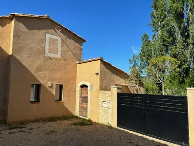 a house with a black gate and a fence at Maison de charme avec piscine in Simiane-la-Rotonde