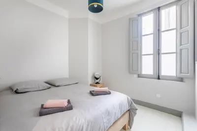 a white bedroom with a large bed with two pillows at Magnifique appartement centre historique in Aix-en-Provence
