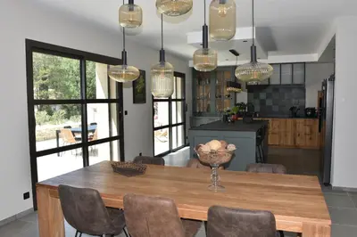 a dining room with a table and chairs and lights at Villa Feijoa en Provence in Velleron