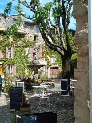 a table and chairs and a fountain in front of a building at Gite LE PETIT LUBERON COQUELICOT in Coustellet