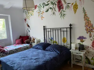 a bedroom with a bed with blue sheets and flowers on the wall at Chambre privée dans un MAS au centre du Village in Maubec