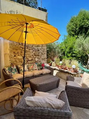 a patio with a yellow umbrella and wicker furniture at Chambre privée dans un MAS au centre du Village in Maubec