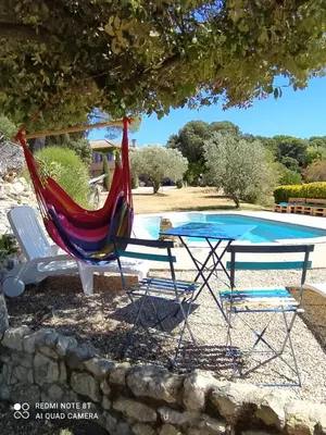 a hammock and a table and chairs next to a pool at La maison de Nazig in Pertuis