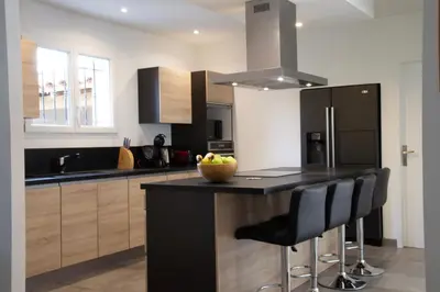 a kitchen with a black island with a bowl of fruit on the counter at Maison Loutina, Villa 5 min à pied du centre in LʼIsle-sur-la-Sorgue