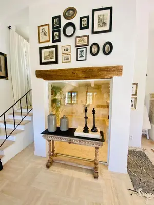 a living room with a fireplace with a shelf of framed pictures at La Villa Ocre Ménerbes in Ménerbes