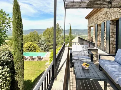 a balcony with a couch and a table and a pool at provence living in Roussillon