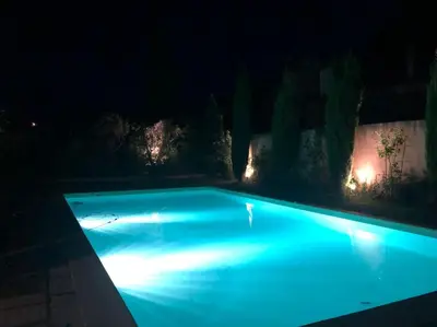 a swimming pool lit up at night with lights at Villa de Minna in Robion en Luberon