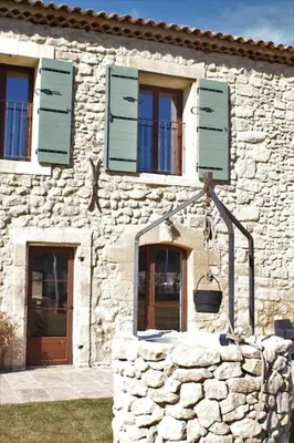 a stone building with green shutters on it at Mas en campagne in Mallemort