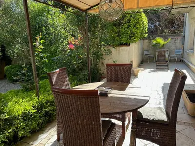 a patio with a wooden table with chairs and an umbrella at Nid d'Ange en Provence in Cavaillon