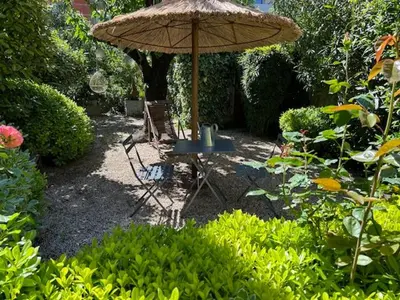 a table and chair under an umbrella in a garden at Nid d'Ange en Provence in Cavaillon