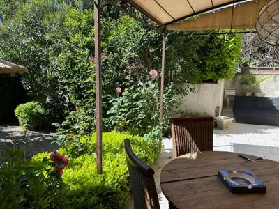 a wooden table under an umbrella in a garden at Nid d'Ange en Provence in Cavaillon