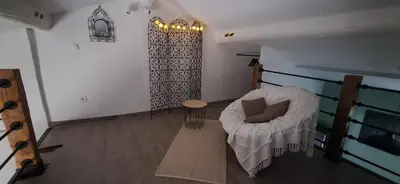 a living room with a white chair and a table at Loft en duplex au Mas de la Restanque in Monteux