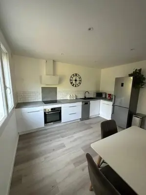 a kitchen with white cabinets and a table and a clock at L’Amistouso in Vedène
