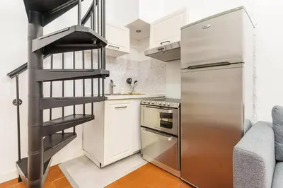 a kitchen with a stainless steel refrigerator and a spiral staircase at Duplex en plein centre historique Aix en provence in Aix-en-Provence