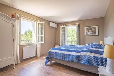 a bedroom with a blue and white bed and two windows at Villa des Fontaines luxury family home with pool in Pernes-les-Fontaines