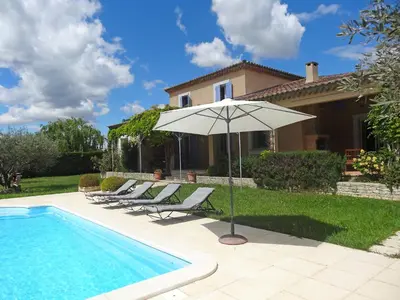 a pool with chairs and an umbrella next to a house at Villa Le Bouloulou by Interhome in Velleron