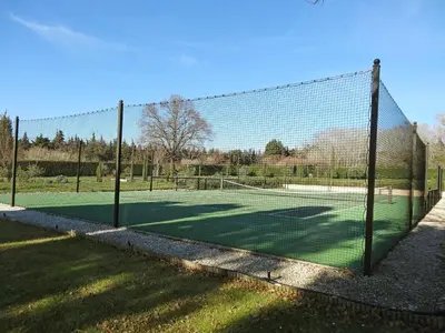 a tennis court with a net in the grass at Villa Le Bouloulou by Interhome in Velleron